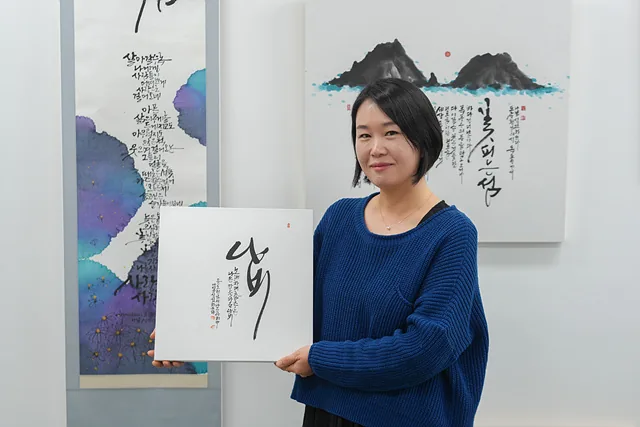 작품을 들고 서 있는 신선하 작가