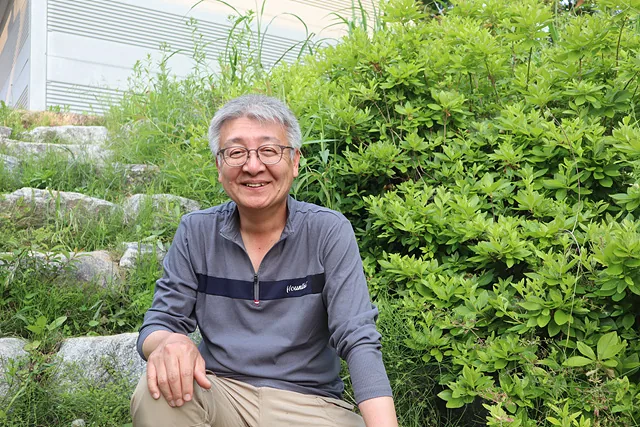 계단에 걸터앉아 웃고 있는 김민근 씨.