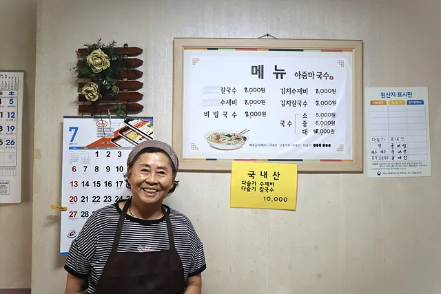 #메뉴판 앞에서 웃고 있는 박숙자 사장