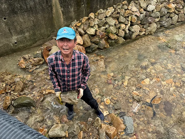 이종철 어르신이 도랑이 넘치지 않게 돌을 치우고 있다.
